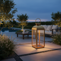 Brushed brass outdoor lantern styled on a luxury garden terrace at dusk